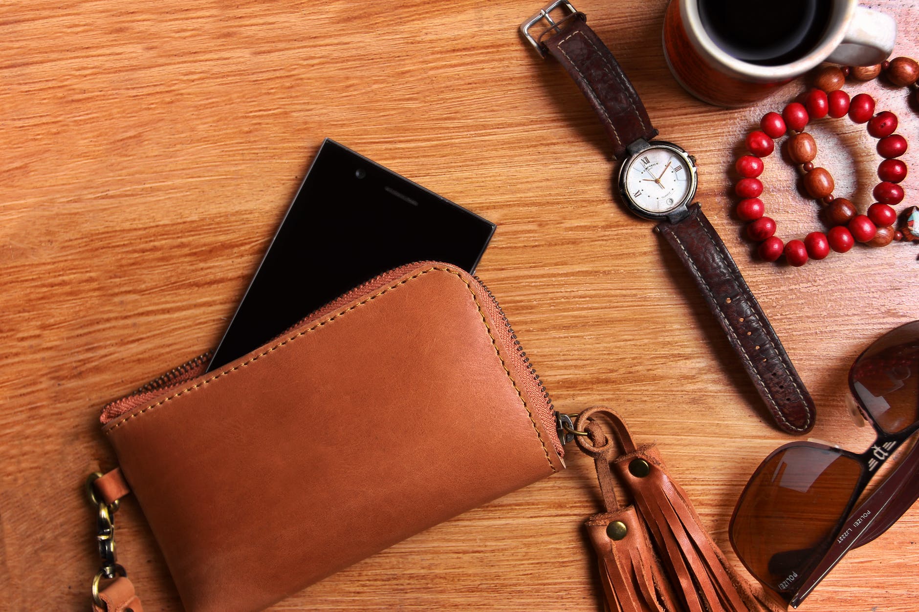 Ethical and Sustainable Leather Guide - brown leather wallet with phone, watch, and key on wood table