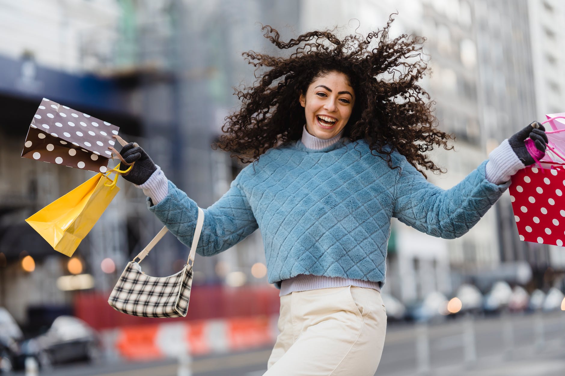 happy woman jumping with shopping bags - Should Sustainable Fashion Be Fun