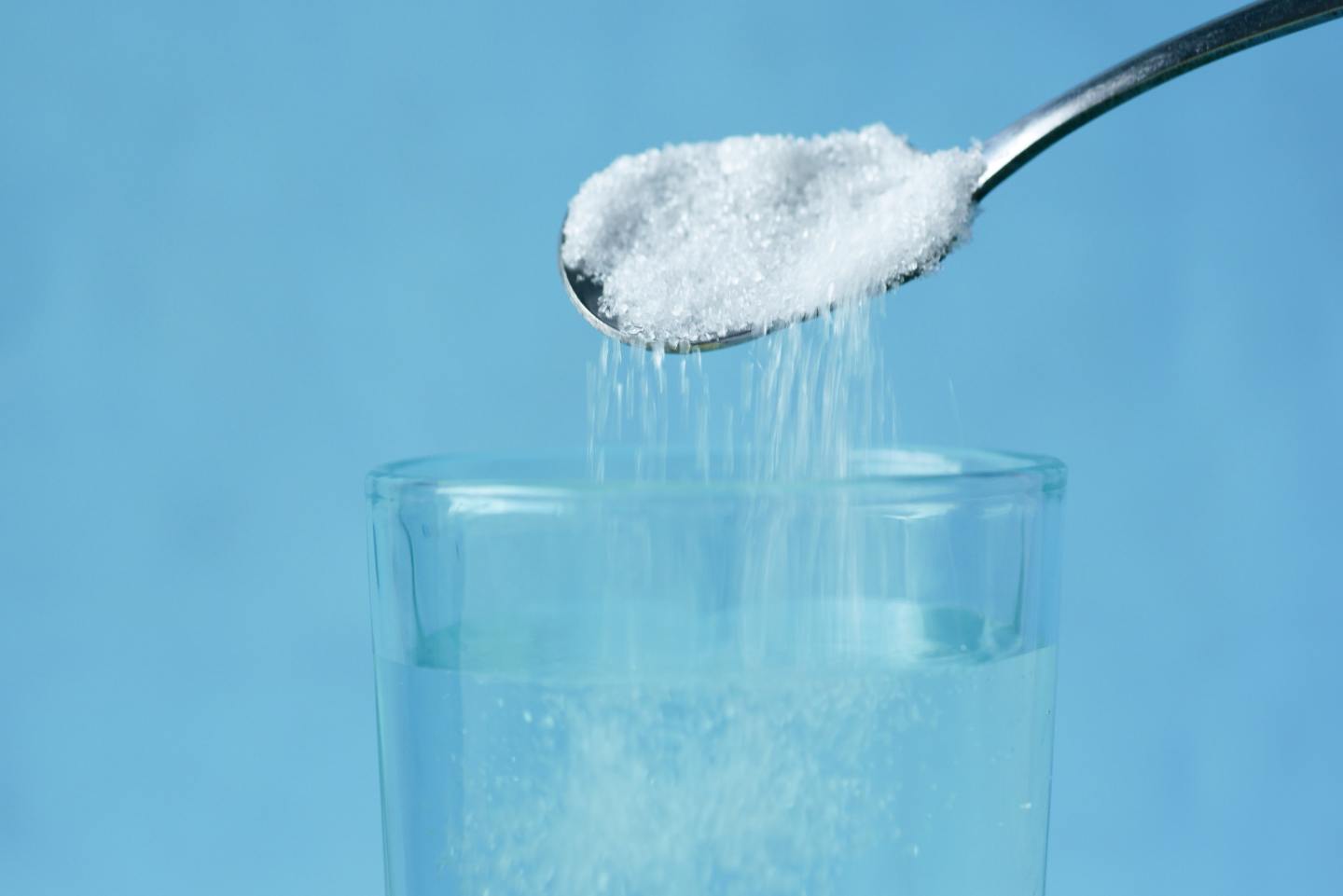 salt on spoon being poured into glass of water