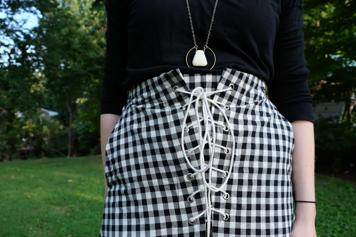 Gingham + Impulse Buys - closeup shot of black shirt and gingham skirt with long necklace with white pendant