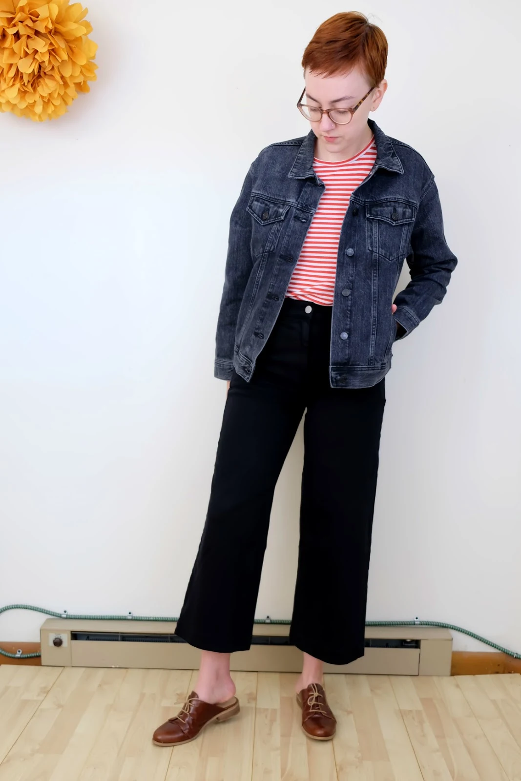 Leah wears a washed black Everlane jacket with black pants and a red striped shirt - Everlane Denim Jacket Review