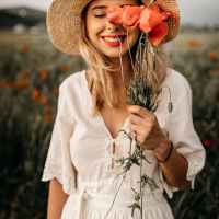 charming woman in hat with flowers in meadow