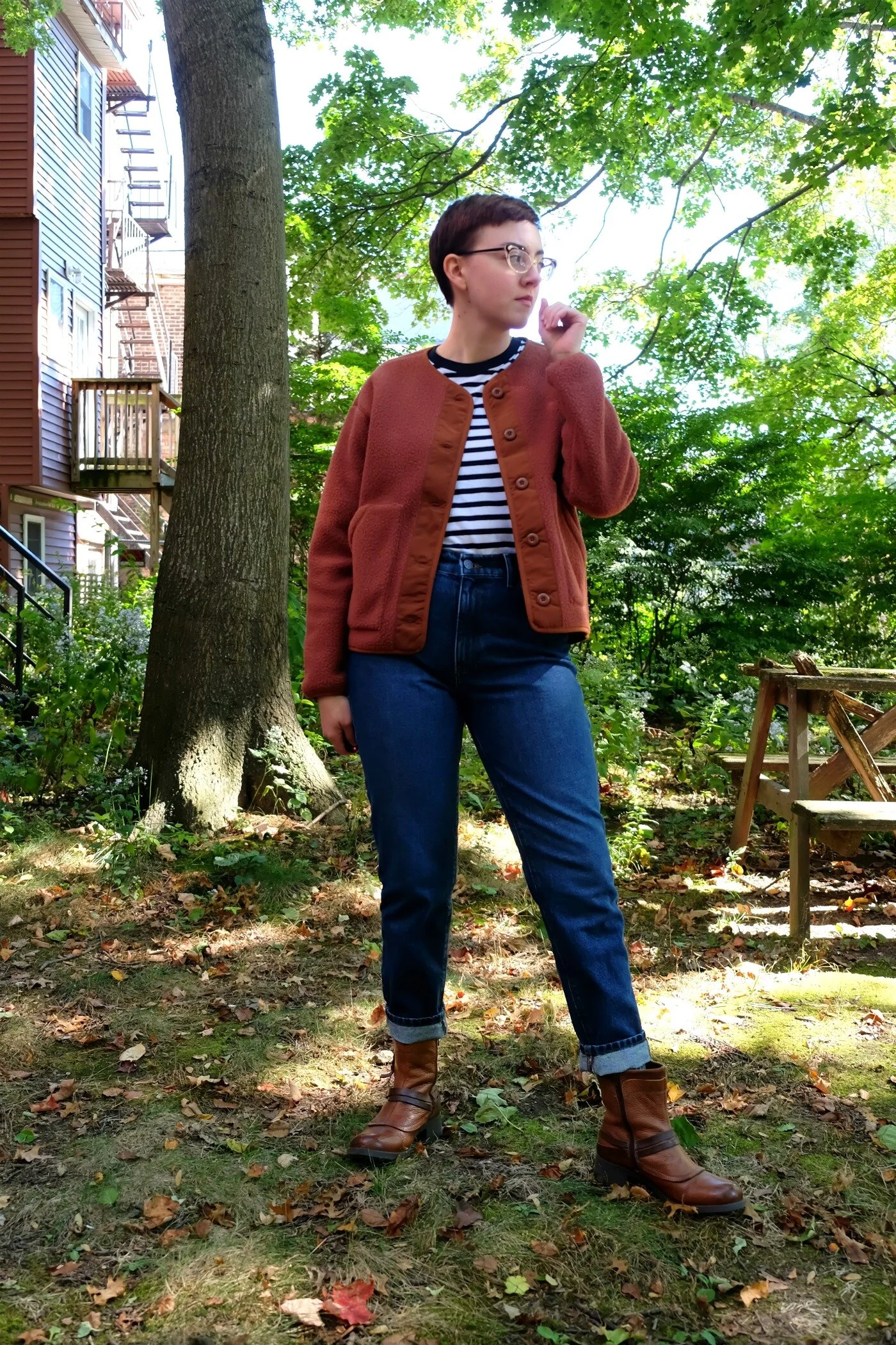 Leah wears a striped shirt with jeans, boots, and an orange brown fleece jacket - Everlane ReNew Teddy Liner