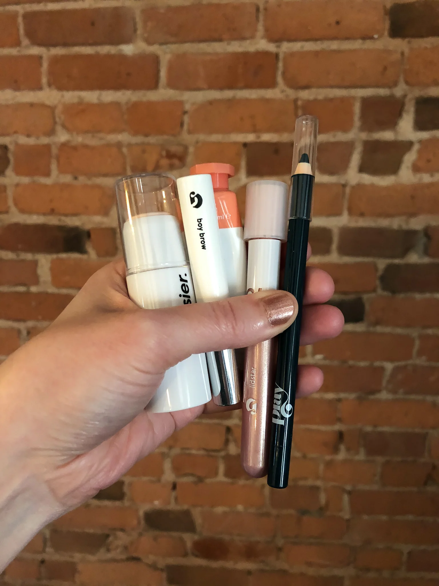 hand holding five glossier products - Glossier Boy Brow Review