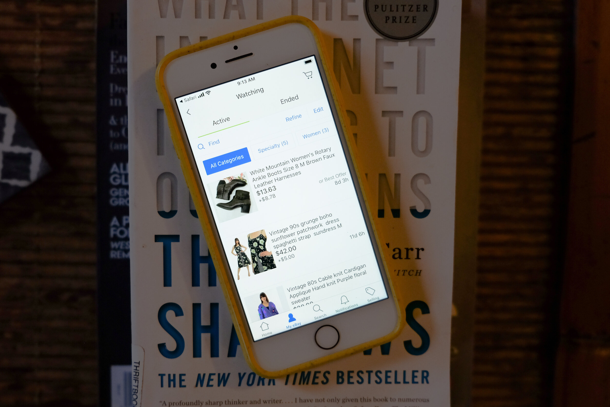 phone showing Ebay app stacked on books - Ebay vs. Poshmark Comparison