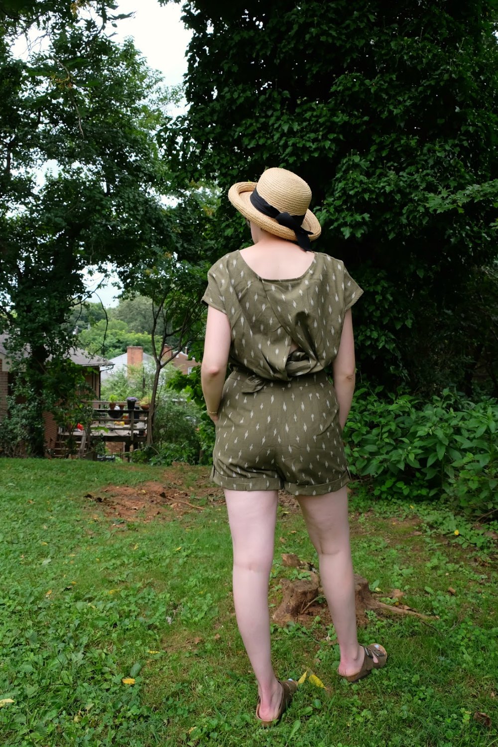 Leah stands in yard wearing a green romper and straw hat - Cultural Appropriation in Fashion