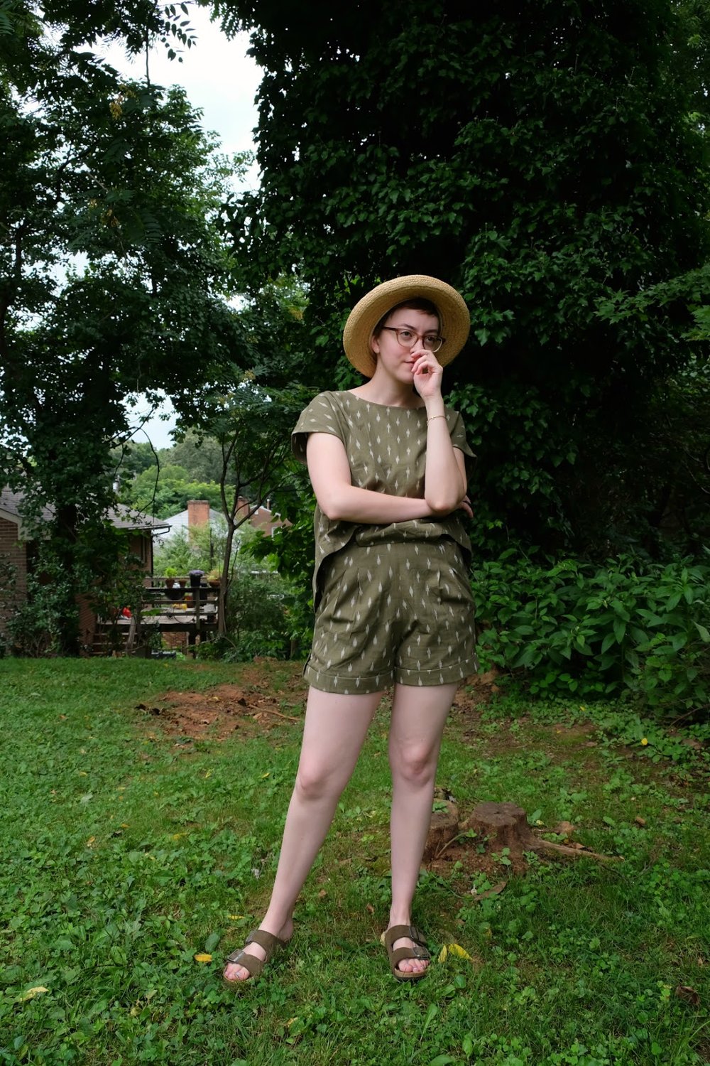 Leah stands in yard wearing a green romper and straw hat - Cultural Appropriation in Fashion