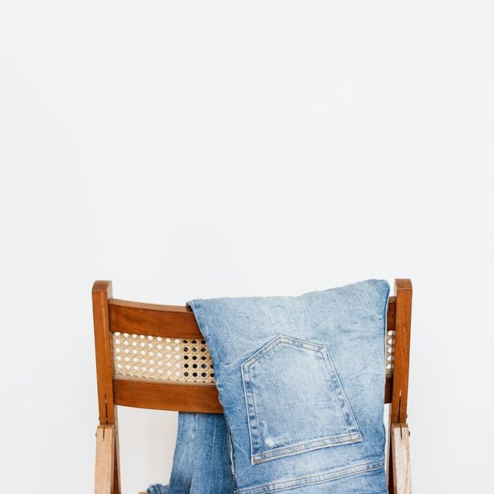 stylish jeans hung on wooden chair