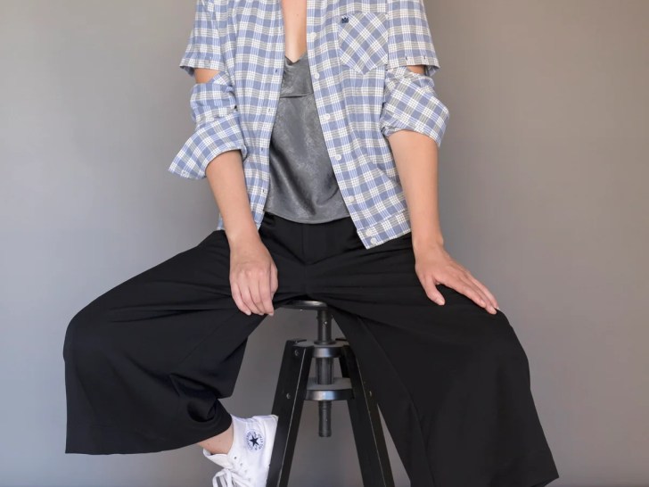 Kindom convertible upcycled gingham top worn by a woman wearing black pants and sitting on a bench
