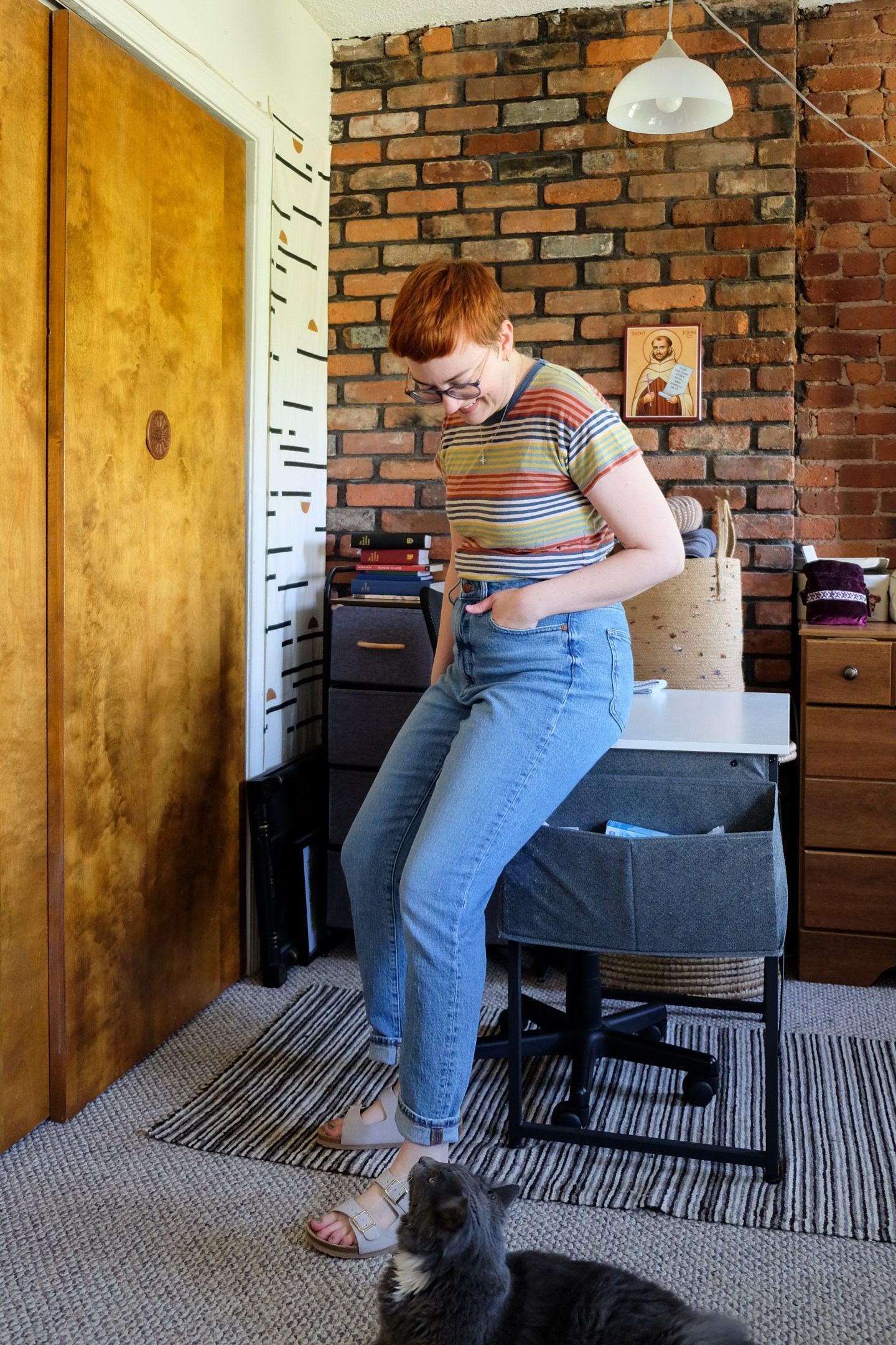 Leah stands in her bedroom wearing a striped shirt, light wash jeans, and sandals - Summer Favorites