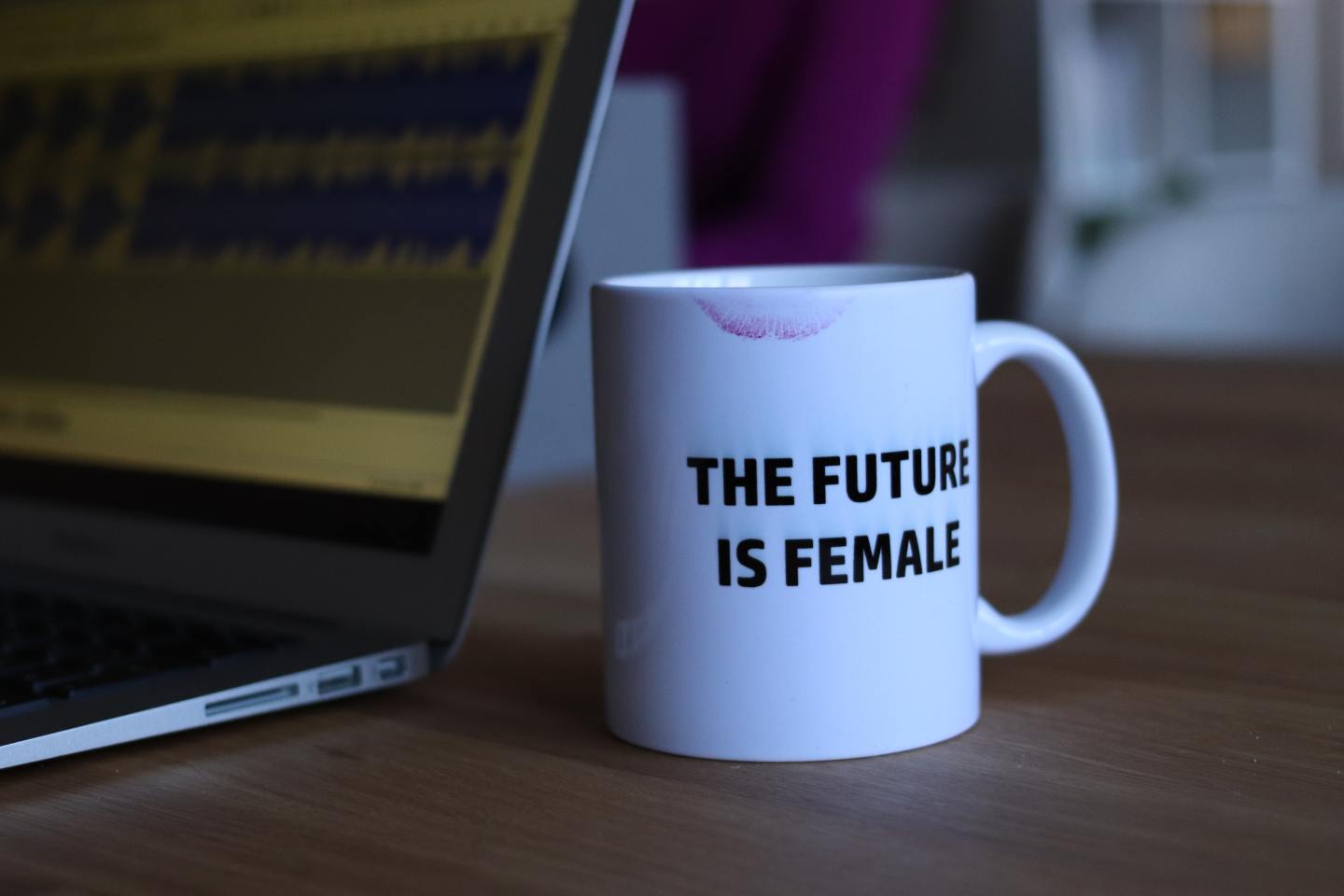 white mug that reads "The Future is Female" setting on desk next to computer - Why Fashion Is Political