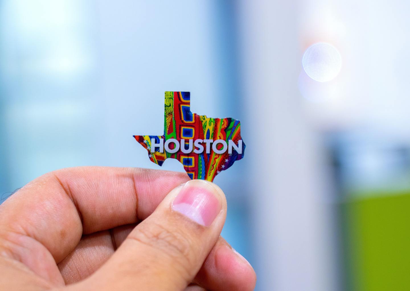 closeup of hand holding a sticker in the shape of Texas that reads "Houston." - Thrift Stores in Houston Guide