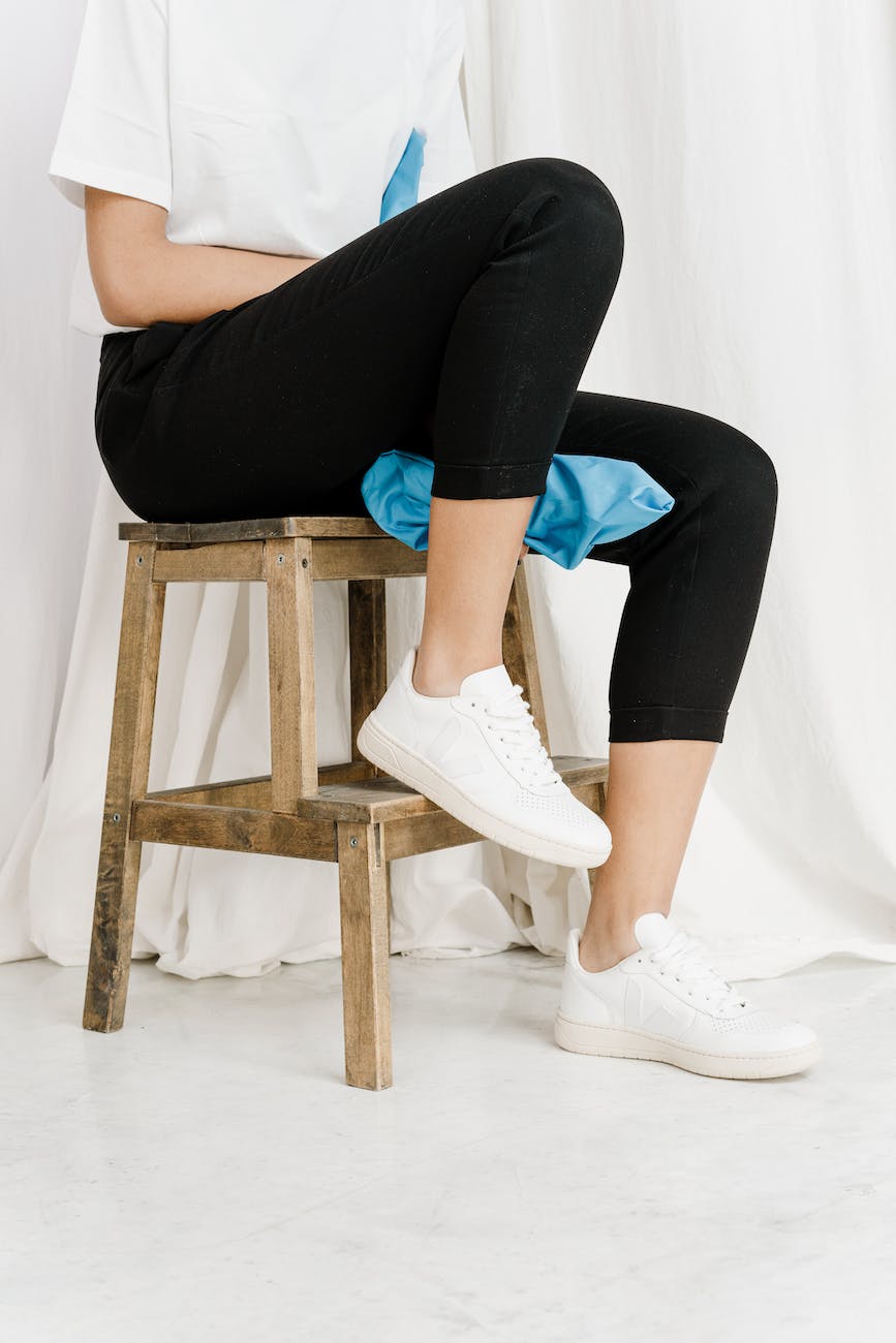 person in black leggings and white sneakers sitting on brown wooden stool - Lead in Shein Clothing